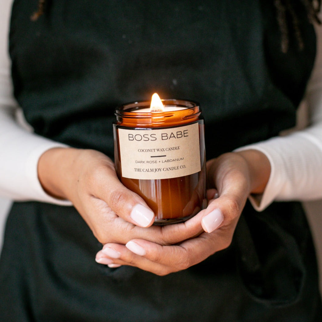 Dark Rose Bud Vanilla Candle Held in Front of an Apron