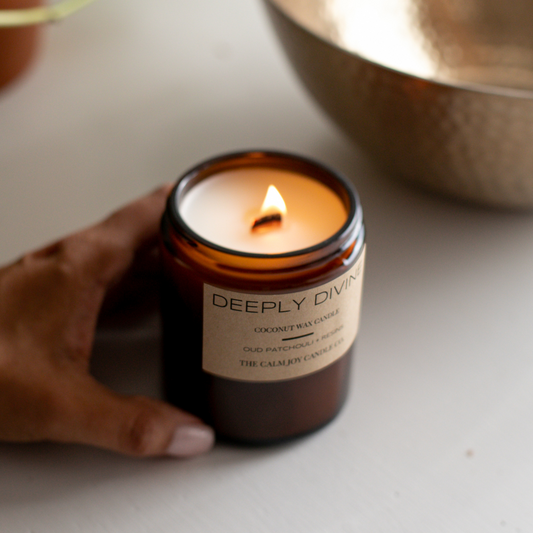 amber patchouli citrus candle being held by a hand on a white table