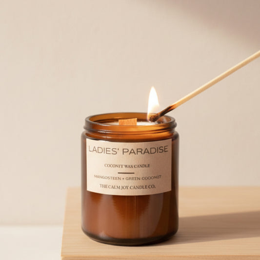 Candle labeled 'Ladies' Paradise' being lit with plants in the background